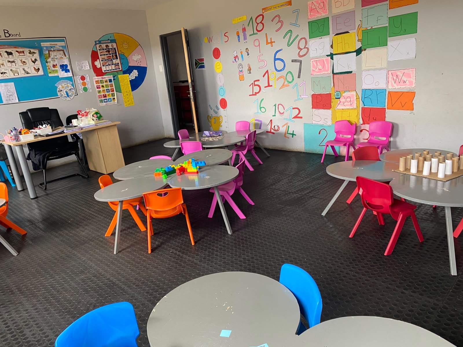 The Busy Bees classroom with clover tables and the vowels wall