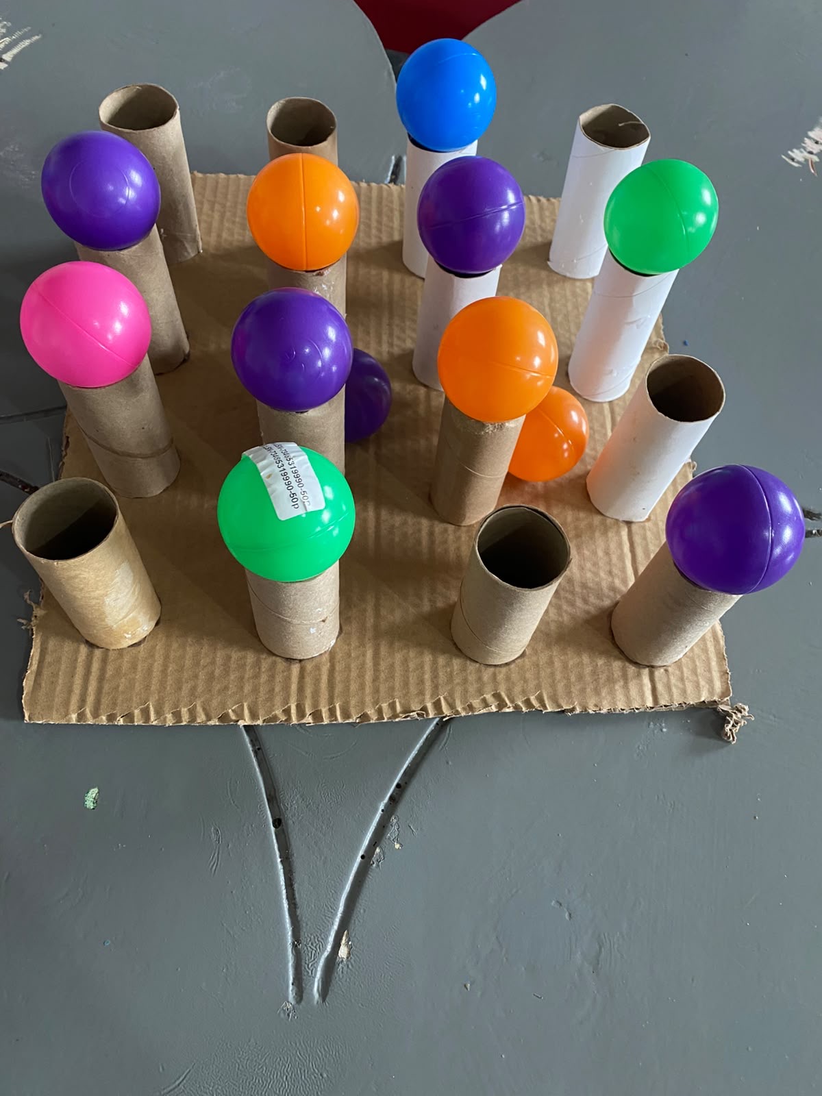 A hand-made fine-motor toy built from cardboard tubes and balls