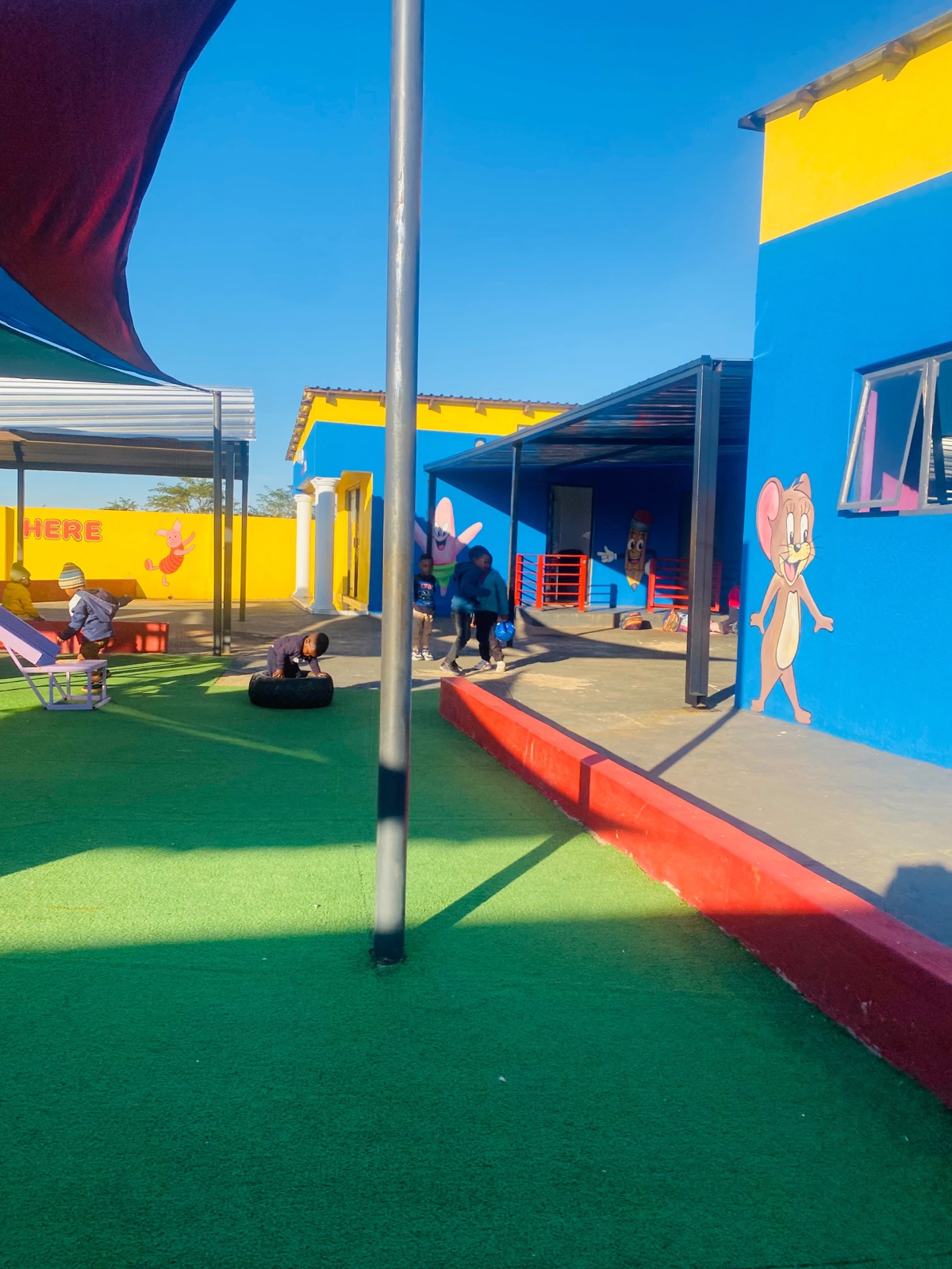 Children playing on the artificial grass under shade sails in the yard